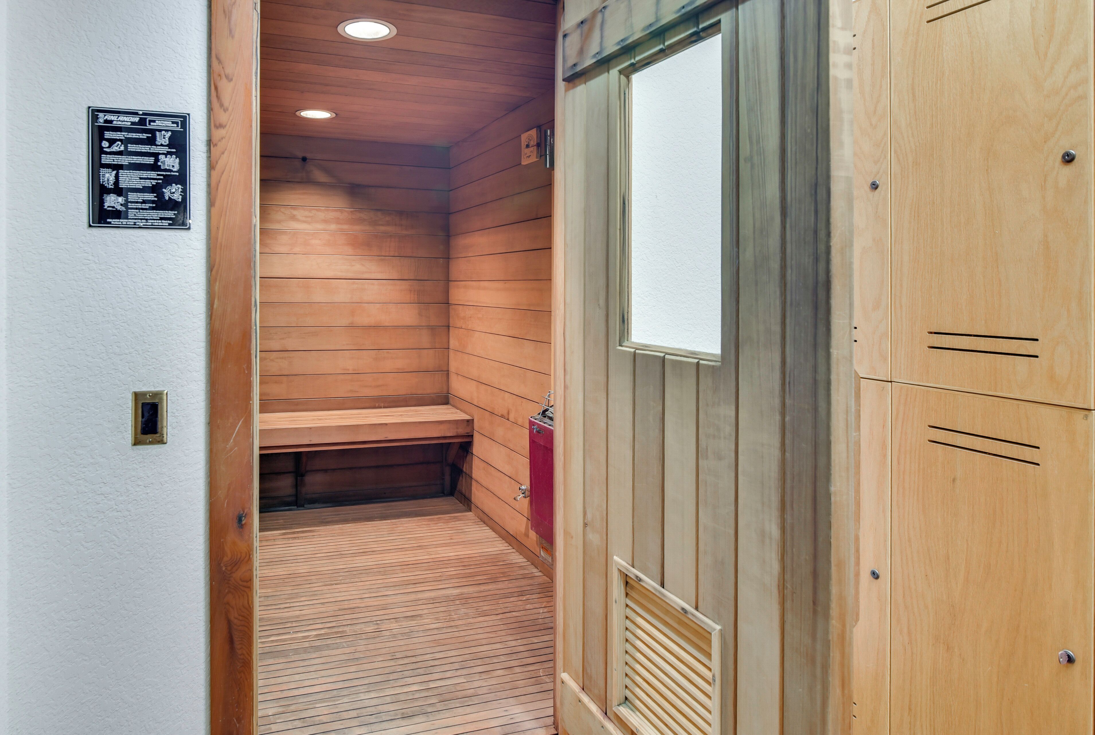 Una sala de sauna con paredes de madera y un banco, una puerta de madera y un sistema de ventilación.