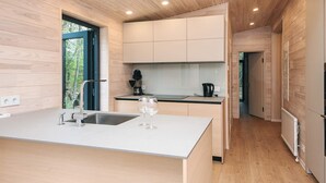 A modern kitchen with wooden cabinetry, a central island with a sink, and a view of the outdoors. - 5 Star Holiday Home in Fjerritslev (Fjerritslev)