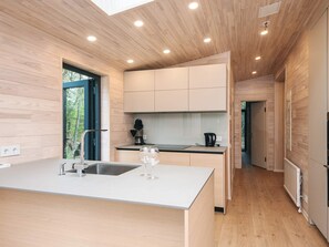 A modern kitchen with wooden cabinetry, a central island with a sink, and recessed ceiling lights. - 5 Star Holiday Home in Fjerritslev (Fjerritslev)