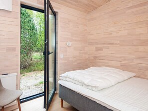A bedroom with a bed, a chair, and a sliding glass door leading to an outdoor area. - 5 Star Holiday Home in Fjerritslev (Fjerritslev)