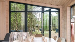 A dining area with a table and chairs, large windows, and a view of the outdoors. - 5 Star Holiday Home in Fjerritslev (Fjerritslev)