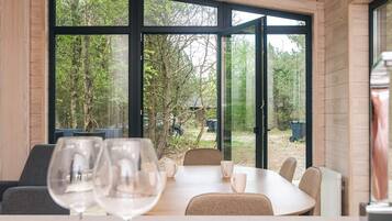 A dining area with a table and chairs, large windows, and a view of the outdoors.