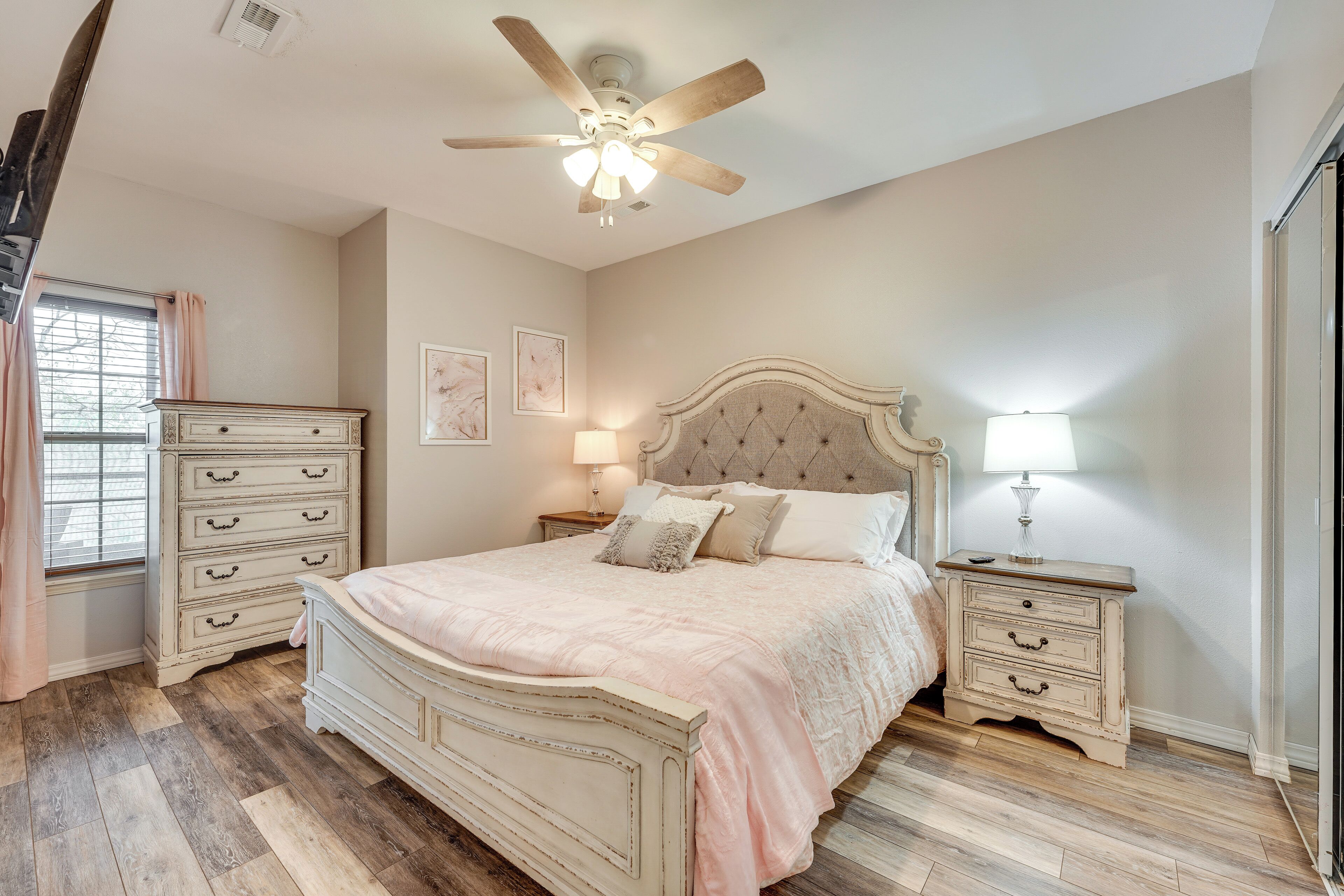 A bedroom with a bed, dresser, nightstands, and a ceiling fan.