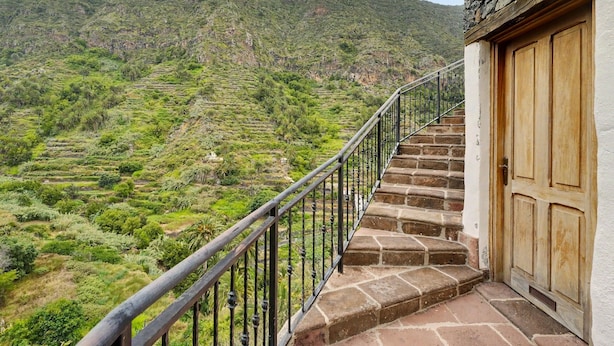 A staircase leading to a wooden door, with a mountain landscape in the background.