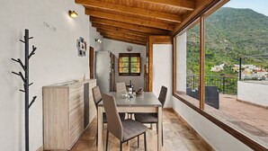 A dining area with a table, chairs, and a view of a mountainous landscape.
