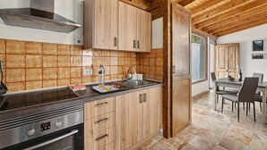 A kitchen with wooden cabinets, a stainless steel range hood, and a dining area with a table and chairs.