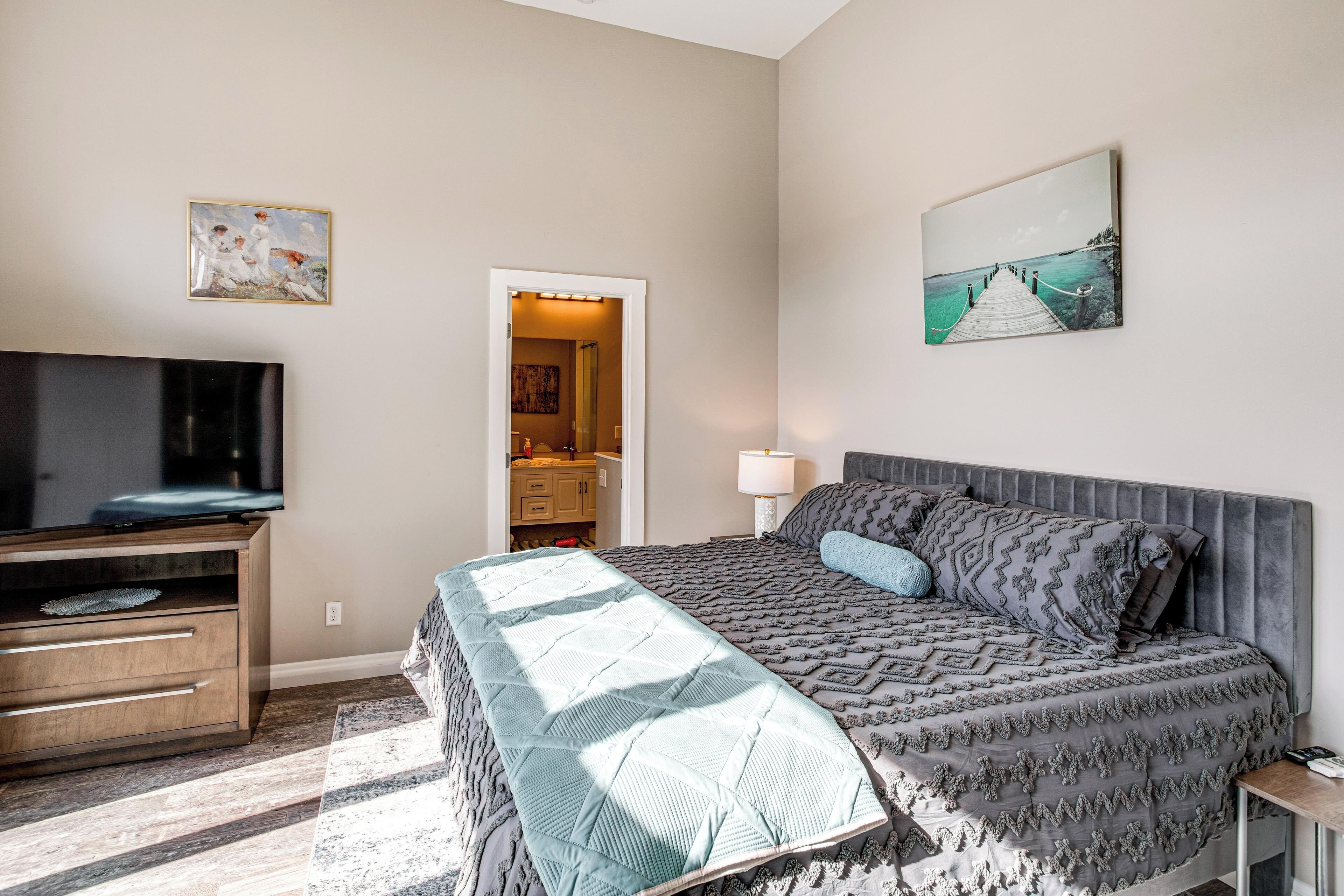 Une chambre à coucher avec un lit, une télévision, une commode et des œuvres d’art accrochées aux murs.