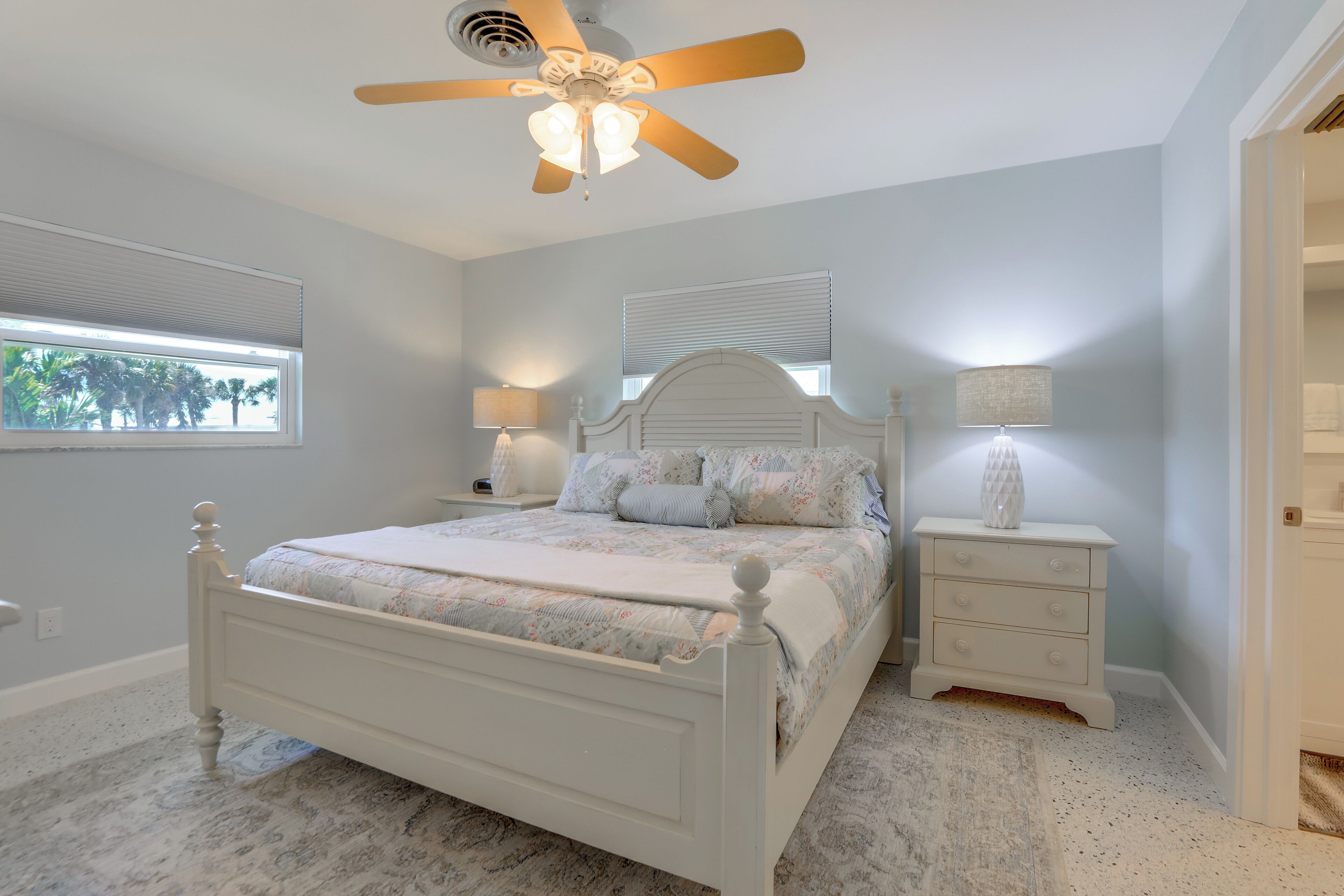A bedroom with a bed, nightstands, a ceiling fan, and a window.