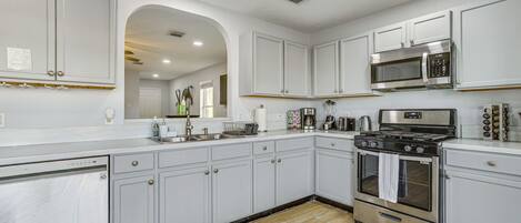A kitchen with white cabinets, stainless steel appliances, and a wooden floor.