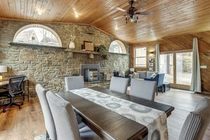 Un comedor acogedor con pared de piedra, techo de madera y chimenea.