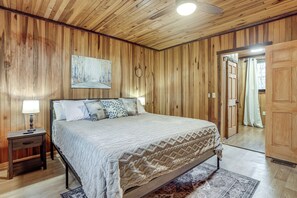 Un dormitorio con paneles de madera, una cama, una mesita de noche y un cuadro en la pared.