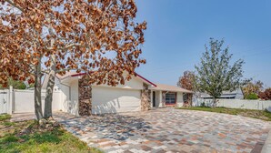 Una propiedad residencial con garaje, entrada de acceso pavimentada y un muro de piedra.