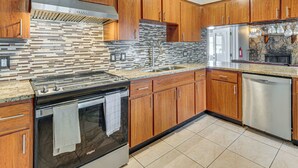 Una cocina moderna con armarios de madera, estufa de acero inoxidable y salpicadero de azulejos.