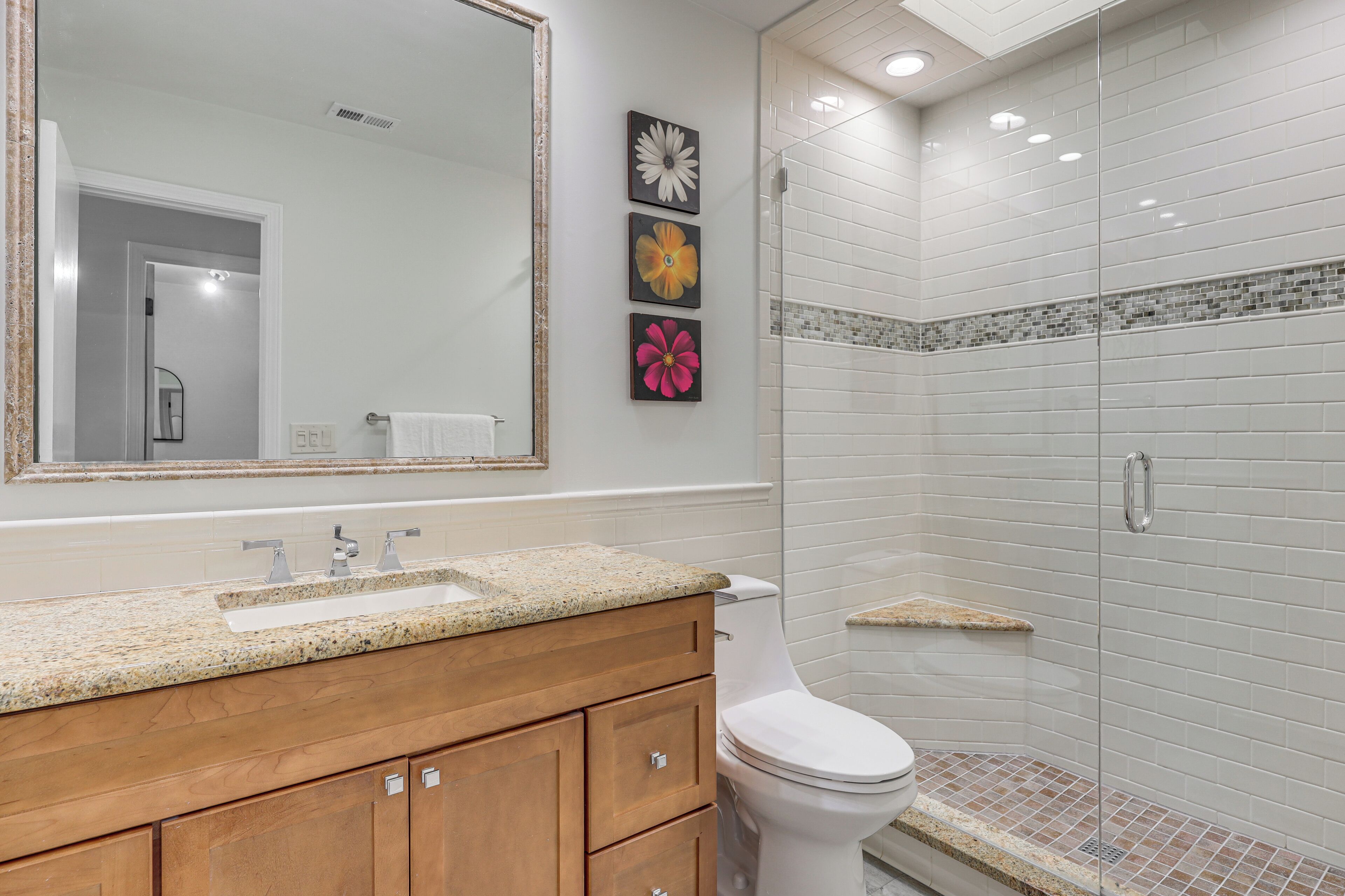 A bathroom with a sink, mirror, toilet, and shower.