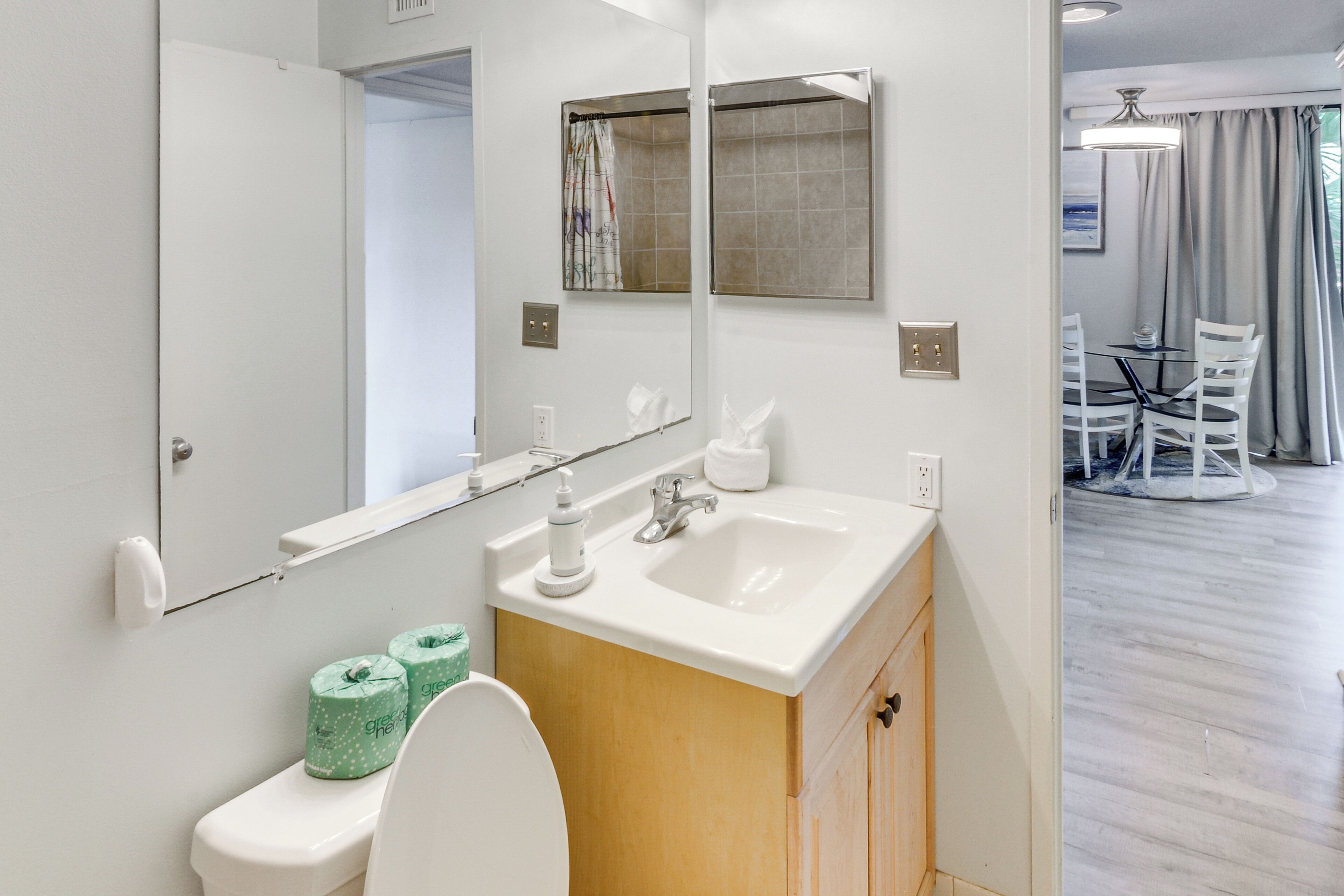 Een badkamer met toilet, wastafel, spiegel en douche.