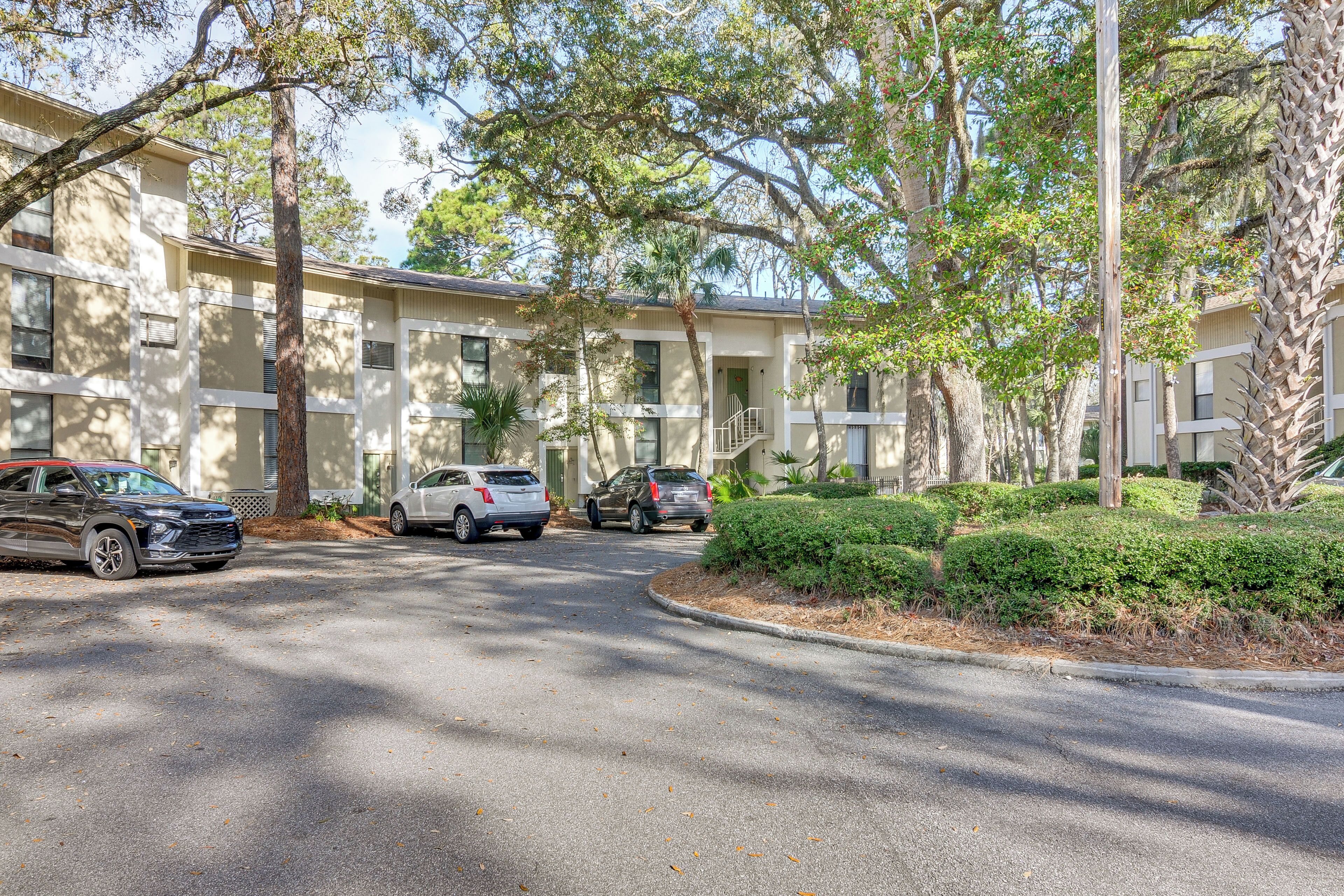 A multi-story building with a parking lot, trees, and a well-maintained lawn.