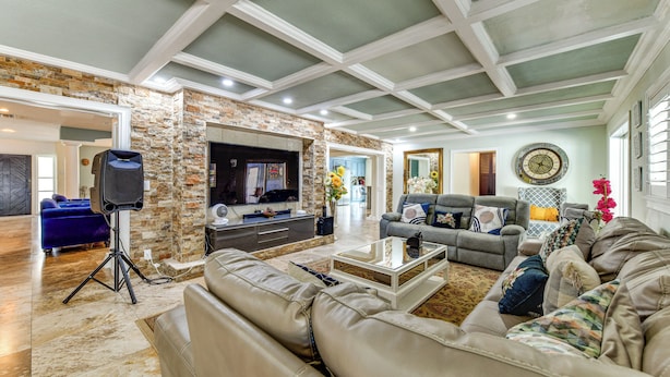 A spacious living room with a stone accent wall, a flat-screen TV, leather sofas, and a coffee table. - 2 Private Pools! 2-acre Retreat Near Dtwn Sarasota (Sarasota)