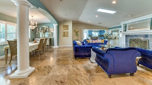A spacious living area with a dining table, blue sofas, and a fireplace. - 2 Private Pools! 2-acre Retreat Near Dtwn Sarasota (Sarasota)