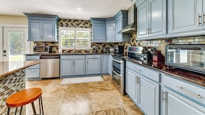 A kitchen with blue cabinets, stainless steel appliances, and a marble floor. - 2 Private Pools! 2-acre Retreat Near Dtwn Sarasota (Sarasota)