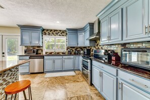 A kitchen with blue cabinets, stainless steel appliances, and a marble floor. - 2 Private Pools! 2-acre Retreat Near Dtwn Sarasota (Sarasota)