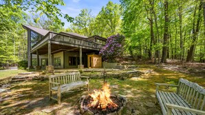 A lodge with a fire pit, wooden benches, and a covered deck. - DuPont Mountain Lodge: 28 Private Acres + Sauna (Cedar Mountain)