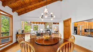 A dining area with a wooden table, chairs, and a chandelier. - DuPont Mountain Lodge: 28 Private Acres + Sauna (Cedar Mountain)