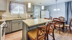 Una cocina con encimeras de granito, sillas de madera, una isla central y una mesa de comedor.