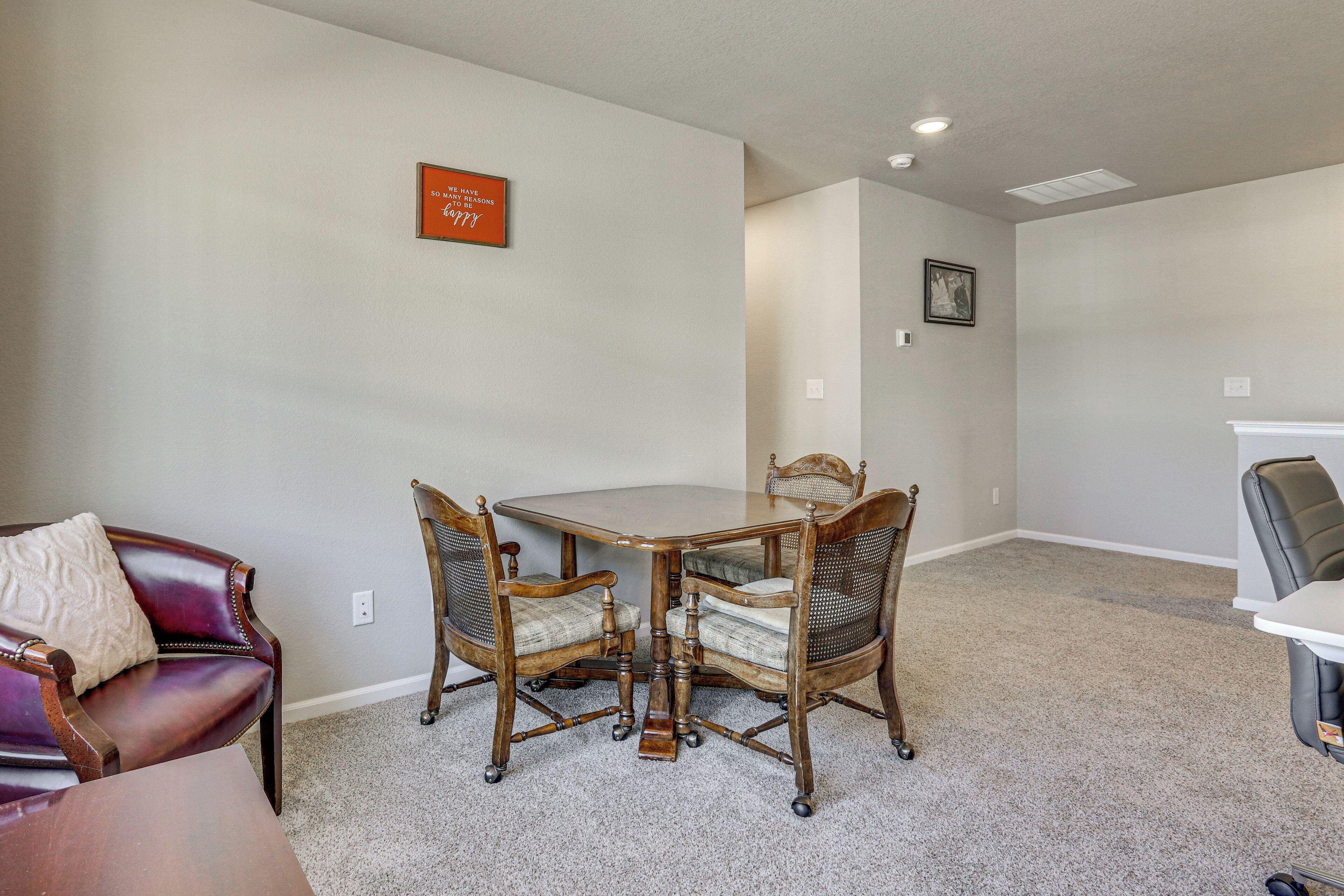A dining area with a wooden table and chairs, a leather sofa, and a framed quote on the wall.