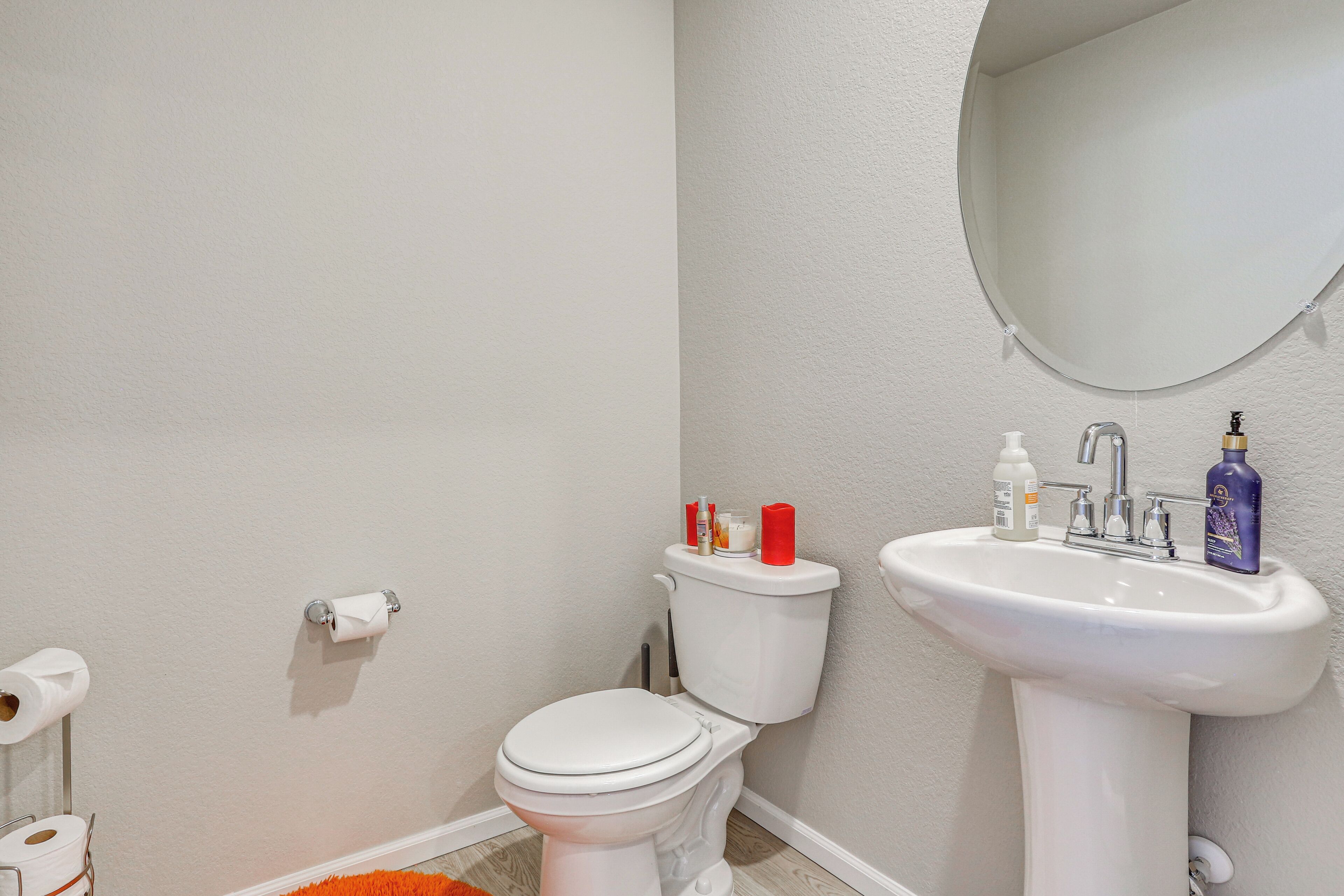 A bathroom with a toilet, sink, and mirror.