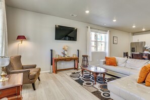 A living room with a sofa, armchair, coffee table, and a TV mounted on the wall. - Work, Play & Explore Denver! Townhome Near Airport (Aurora)