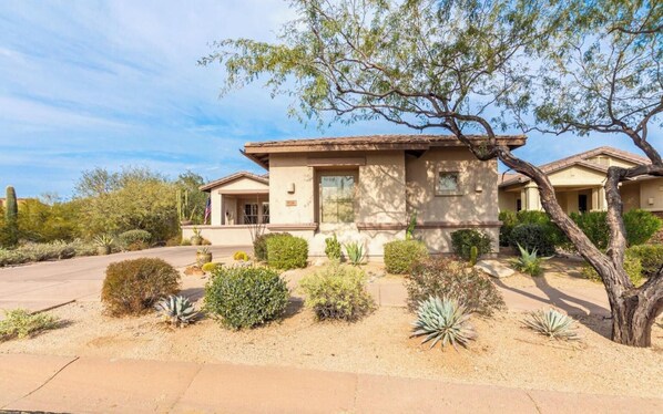 A single-story house with a flat roof, a front porch, and a small front yard with various plants and a tree. - Private Pool Scottsdale Retreat with Covered Patio and Desert Views (Scottsdale)