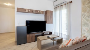 A modern living room with a flat-screen TV, wooden cabinets, a coffee table, and a stone wall.