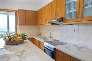 Eine Küche mit Holzausbau, einem Edelstahlbackofen, einer Marmorarbeitsplatte und Blick durch eine Schiebetür.