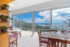 A dining area with a view of a mountainous landscape through large windows. - Medusa Panoramic View Apartment in Georgioupolis (96FW+GW Exopoli)