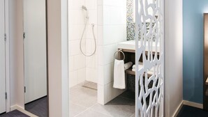 Ein modernes Badezimmer mit Dusche, Toilette und Waschbecken, abgetrennt durch eine dekorative Trennwand.