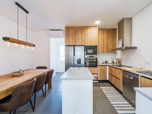 A modern kitchen with wooden cabinets, a stainless steel refrigerator, and a built-in oven.