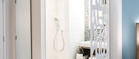 A modern bathroom with a shower, toilet, and sink, separated by a decorative partition.