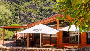 A wooden building with outdoor seating and a mountain backdrop. - Sardinia Hillside Retreat - Apt 13 - 2BR, quiet area, parking (Santa Maria Coghinas)