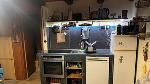 Eine kleine Küche mit eingebautem Ofen, einem Kühlschrank und einem Spülbecken.