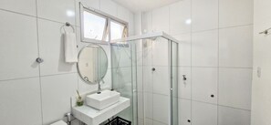 Une salle de bain moderne avec une douche à parois de verre, un lavabo blanc avec un miroir et un porte-serviettes.