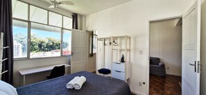 Une chambre d’hôtel équipée d’un lit, d’un bureau, d’une chaise, d’une armoire et offrant une vue sur l’extérieur.