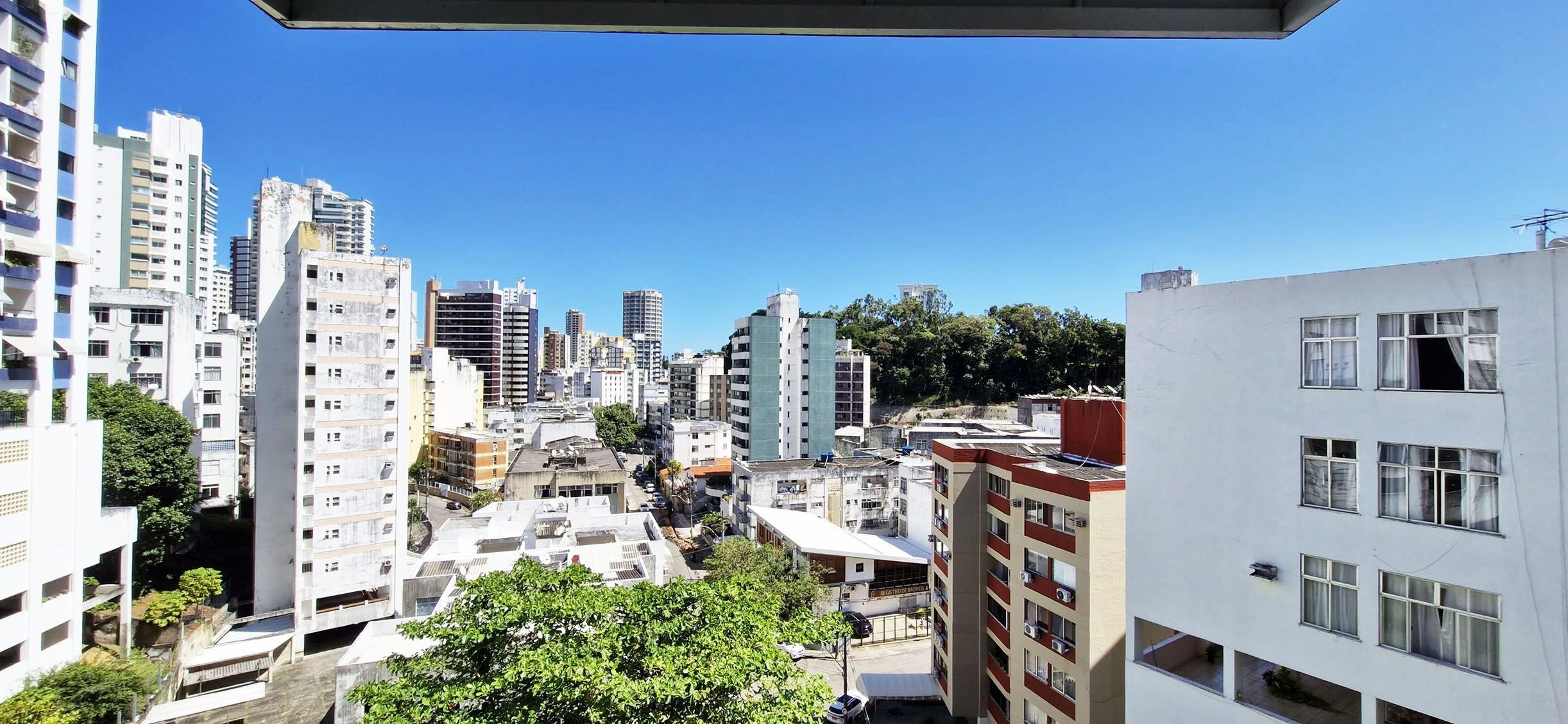 A cityscape with high-rise buildings, a mix of residential and commercial structures, and a clear blue sky.