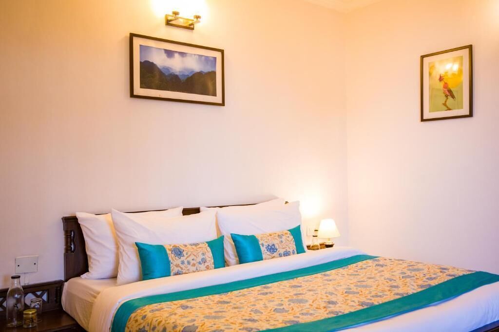 A hotel room with a bed, two wall-mounted lamps, and two framed pictures.