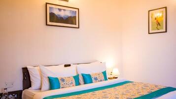 A hotel room with a bed, two wall-mounted lamps, and two framed pictures.