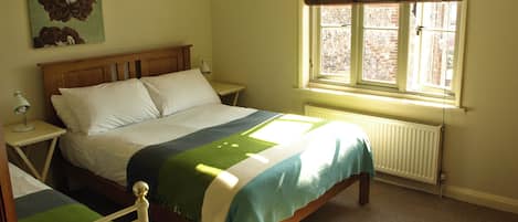 Ein Schlafzimmer mit Bett, Nachttisch, Fenster und Heizkörper.