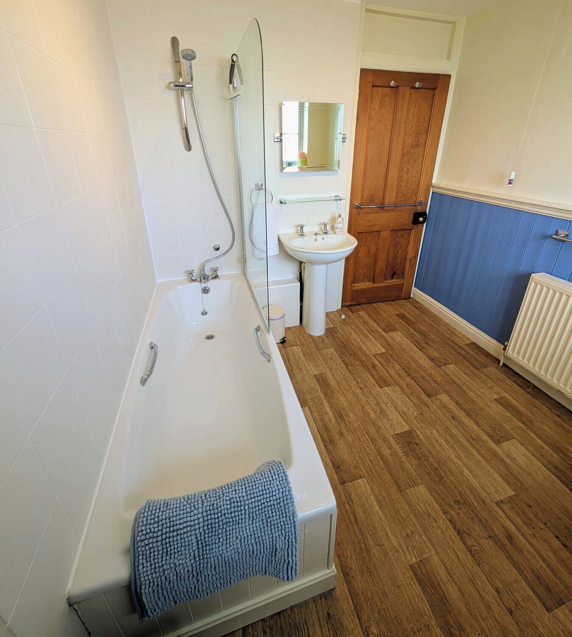 Une salle de bain avec une baignoire, un lavabo, un miroir et une porte en bois.