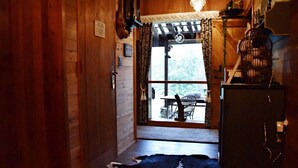 A wooden interior with a cowhide rug, a wooden door, and a view of an outdoor patio. - Brechts Boshuisje Quiet Holiday Home with Sauna (Brecht)