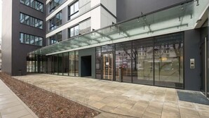 En modern byggnad med en glasfasad, en gångbana med plattor och en dörr med en skylt.
