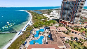 Un resort con una amplia zona de piscina, acceso directo a la playa y un edificio de gran altura.