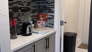 Una cocina con gabinetes grises, una licuadora negra y un salpicadero de azulejos.